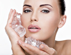 Beautiful young woman applies the ice to face. Skin care concept.